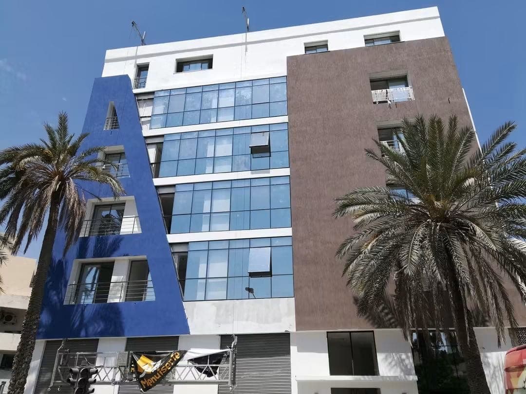 Façade peinte en bleu, blanc et brun autour d’un vitrage, Société Nour